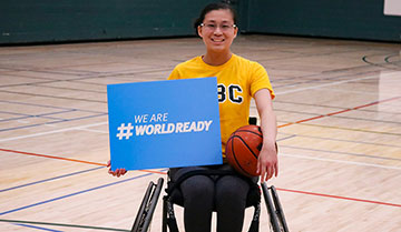 Jeune femme en fauteuil roulant tenant une pancarte